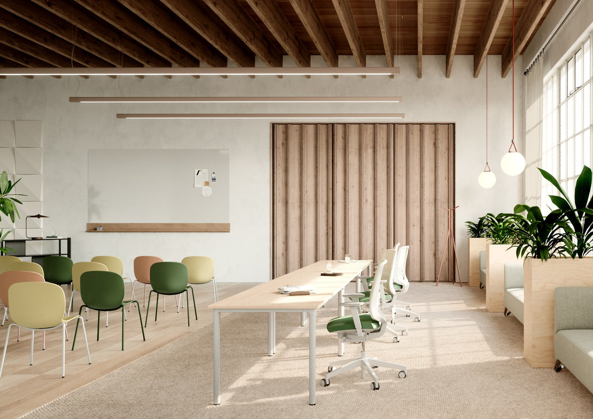 Lichte kantoorinrichting met groene en gele stoelen en houten bureaus